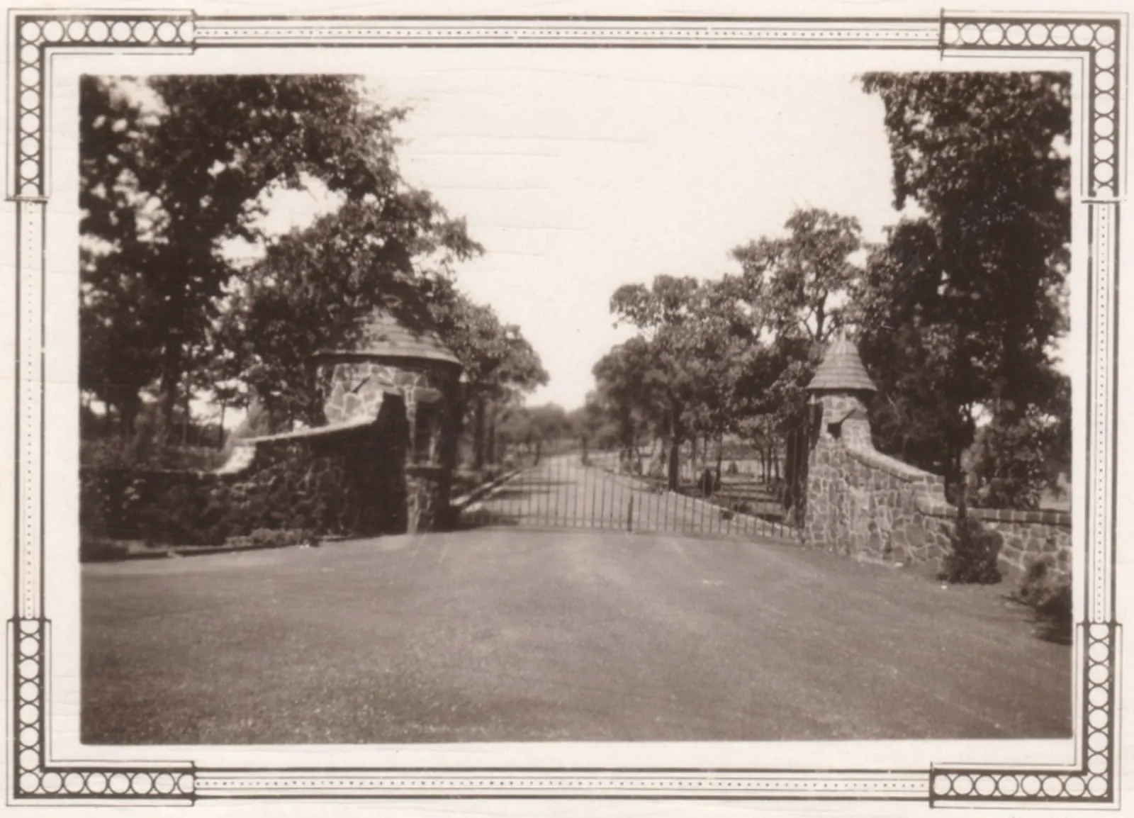 Old photo of the iron gate and stone guardhouses at the Top O’ Hill driveway